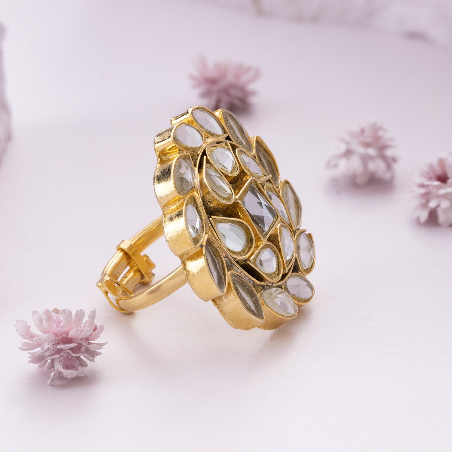 Gold kundan ring on a light pink background with small flowers