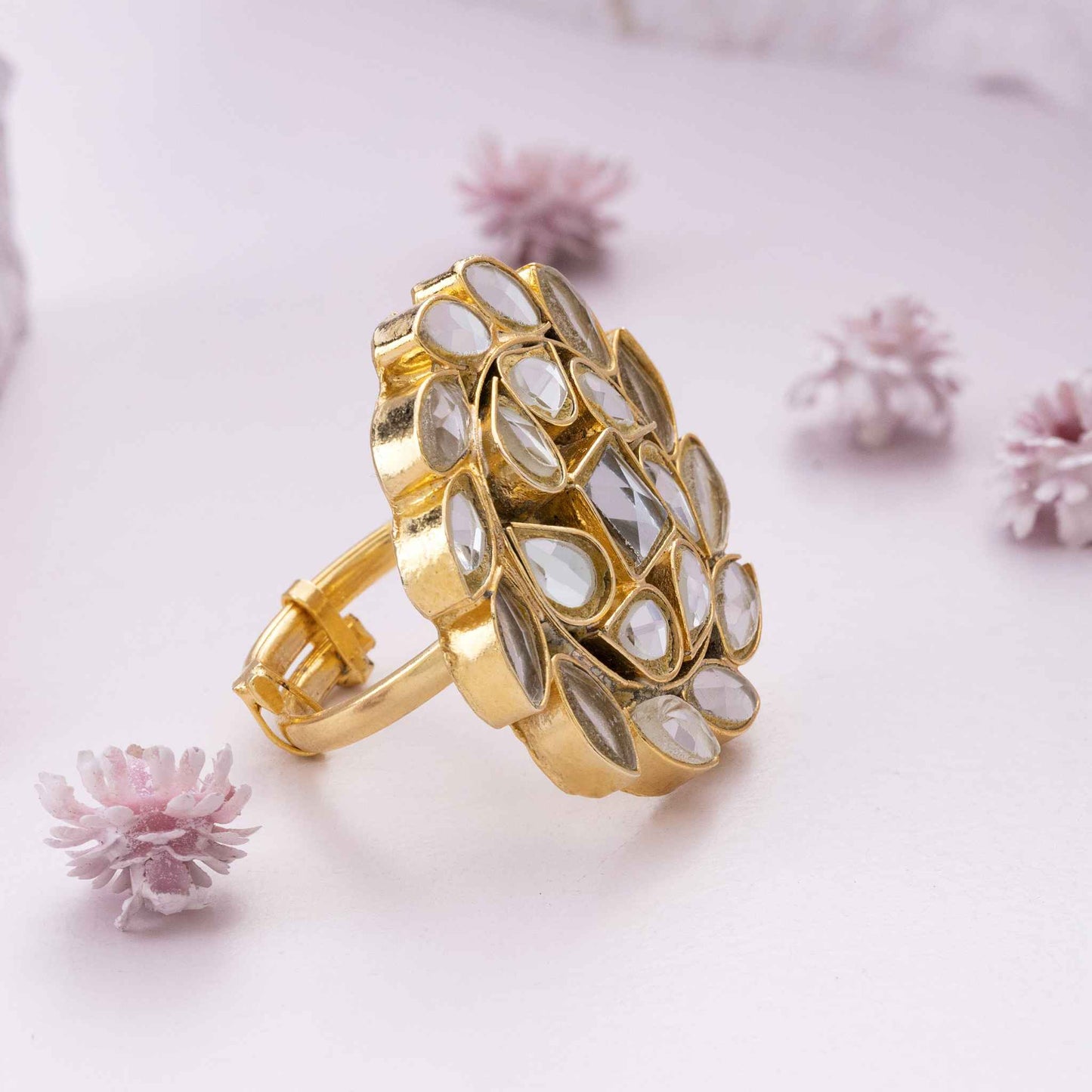 Gold kundan ring on a light pink background with small flowers