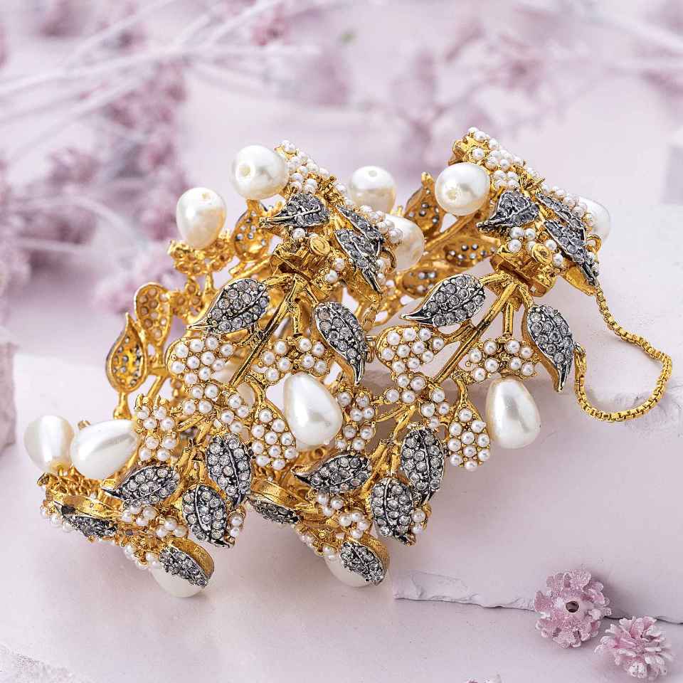 Gold and silver bracelet with pearls on a soft pink background