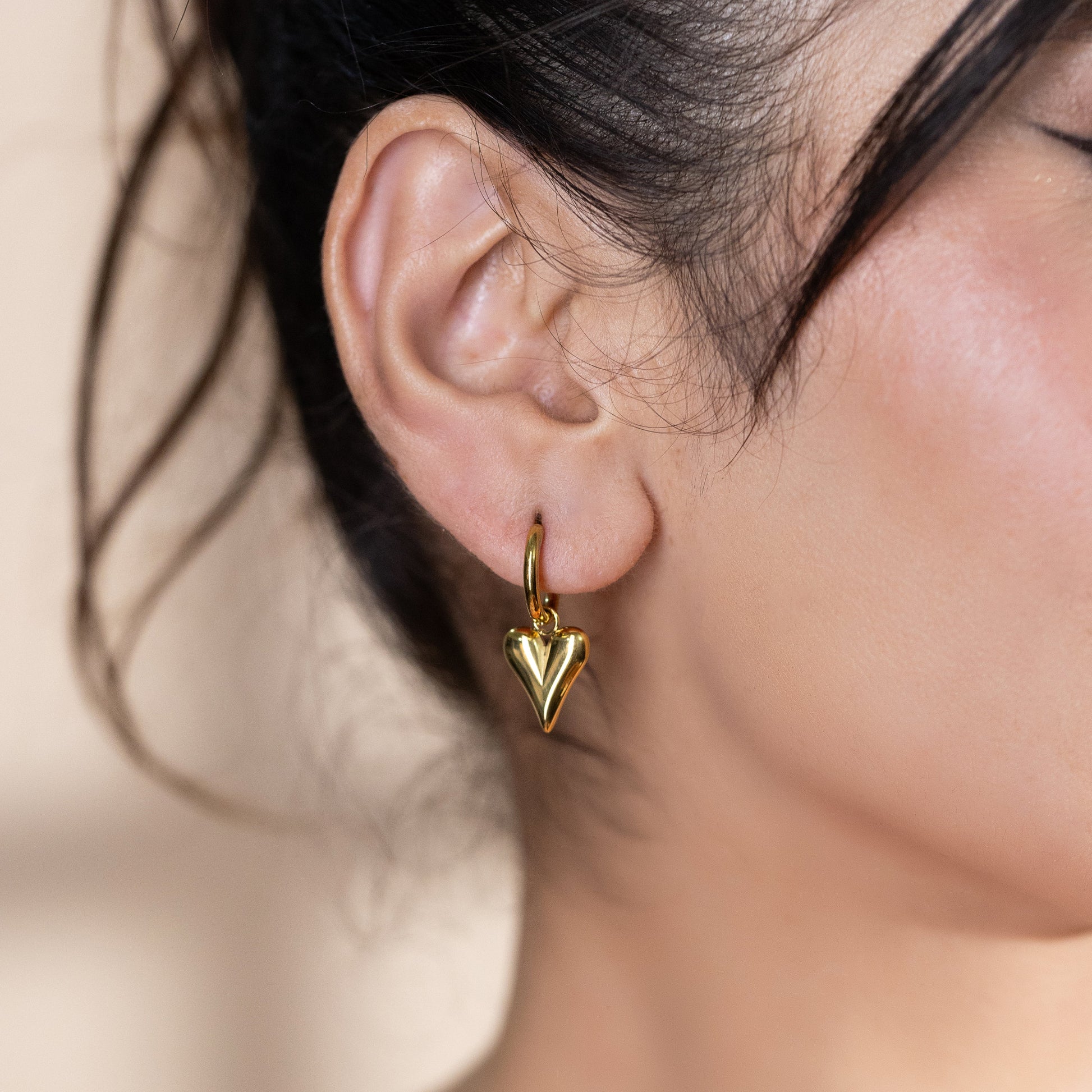 women wearing gold hoop earrings with heart pendant 