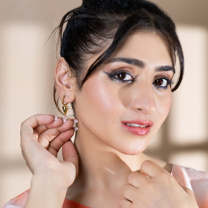 women wearing gold hoop earrings with gold heart charm pendant