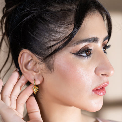 Model showcasing chic heart gold huggie earrings